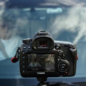 Close-up of a video camera rig mounted in front of a car with reflection of clouds.