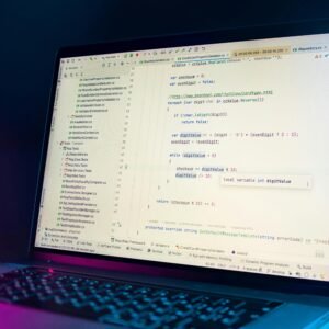 A laptop screen showing a code editor with visible programming code in a dimly lit environment.