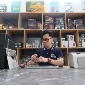 Young technician fixing a computer in a modern electronics store setting.