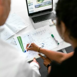 Engineers collaborate on designs with blueprints and laptops in a modern office setting.